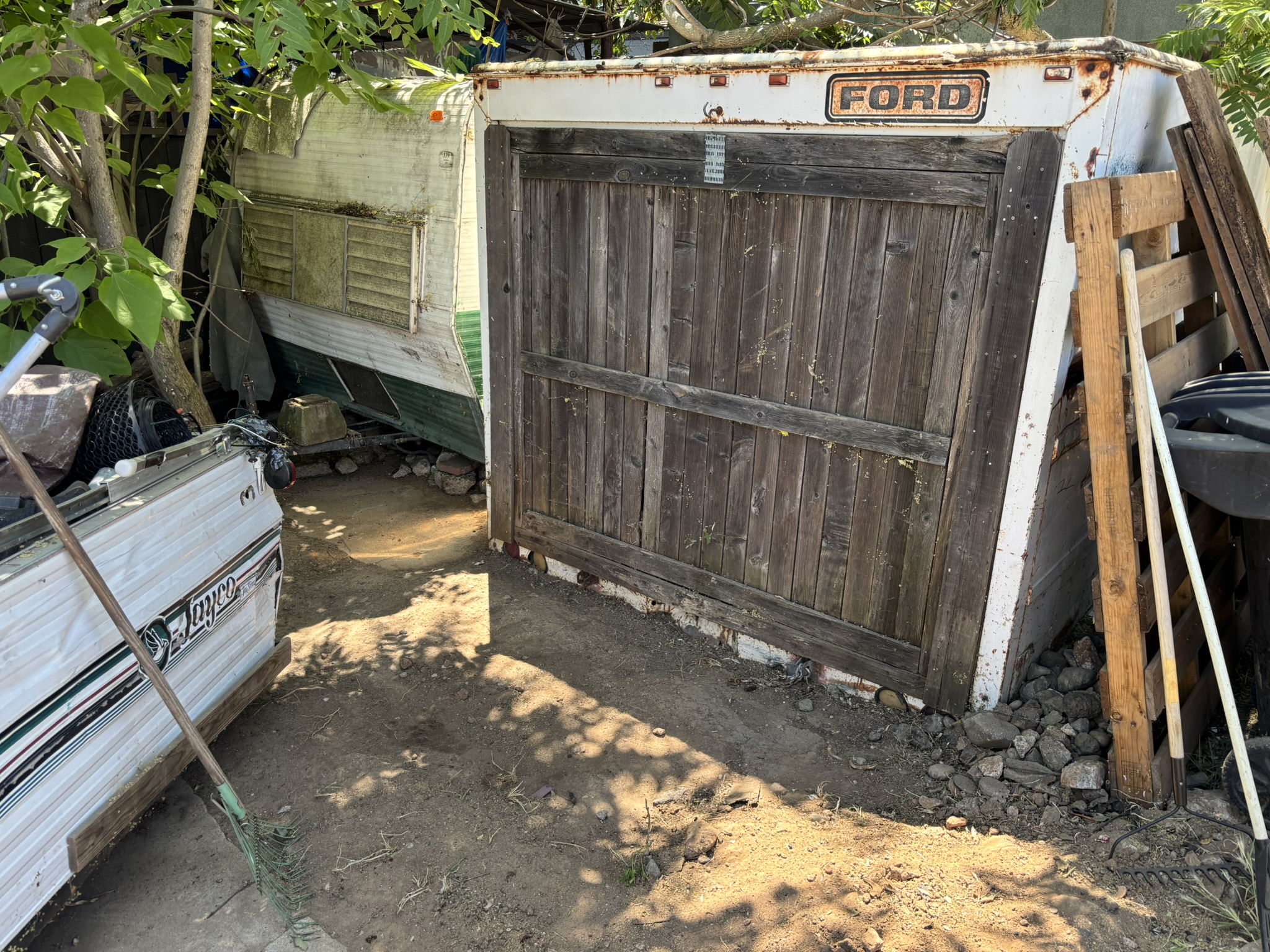 Old Ford truck cap, Jayco trailer, and wood fence panels — junk removal job
