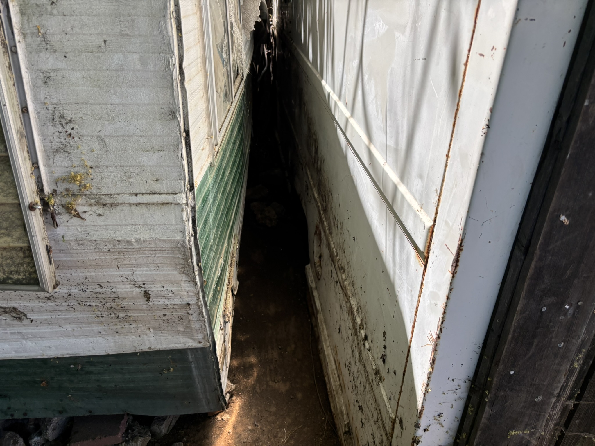Narrow gap between two trailers packed with debris — tight-access cleanup