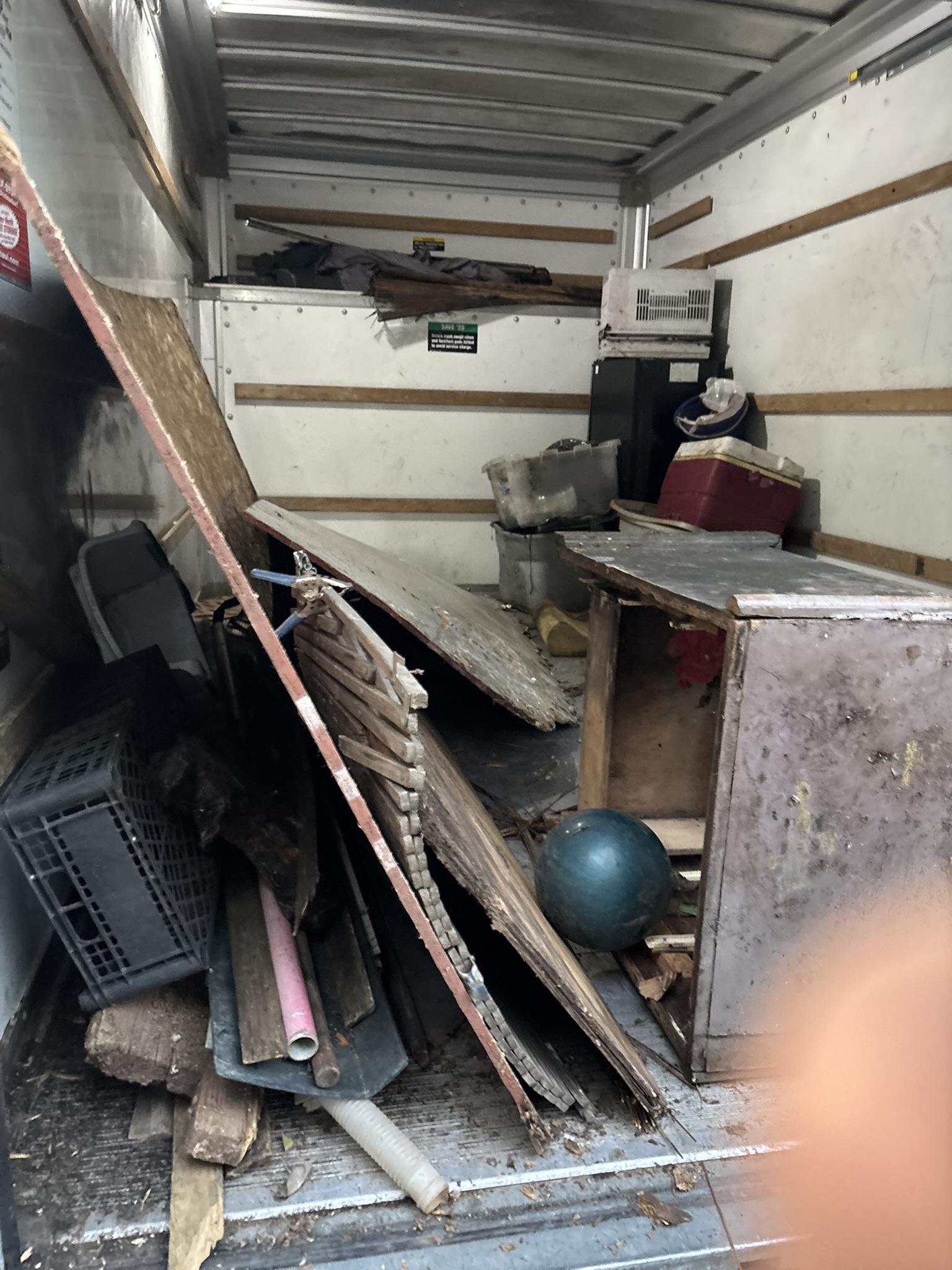 Box truck loaded with lumber, furniture, and junk — property cleanout haul
